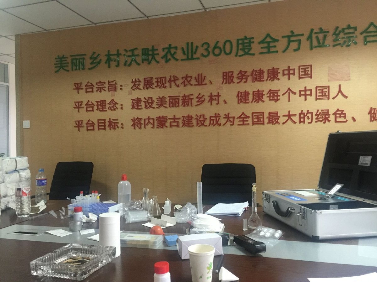Soil sample preparation bench with HM-TYC reagents, microplates, and volumetric flasks during Inner Mongolia training session