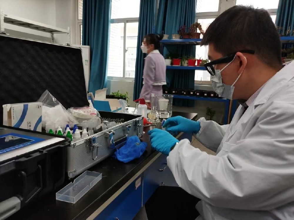 Huainan Normal University instructor demonstrating HM-GT4 soil nutrient analyzer reagent preparation in bioengineering laboratory