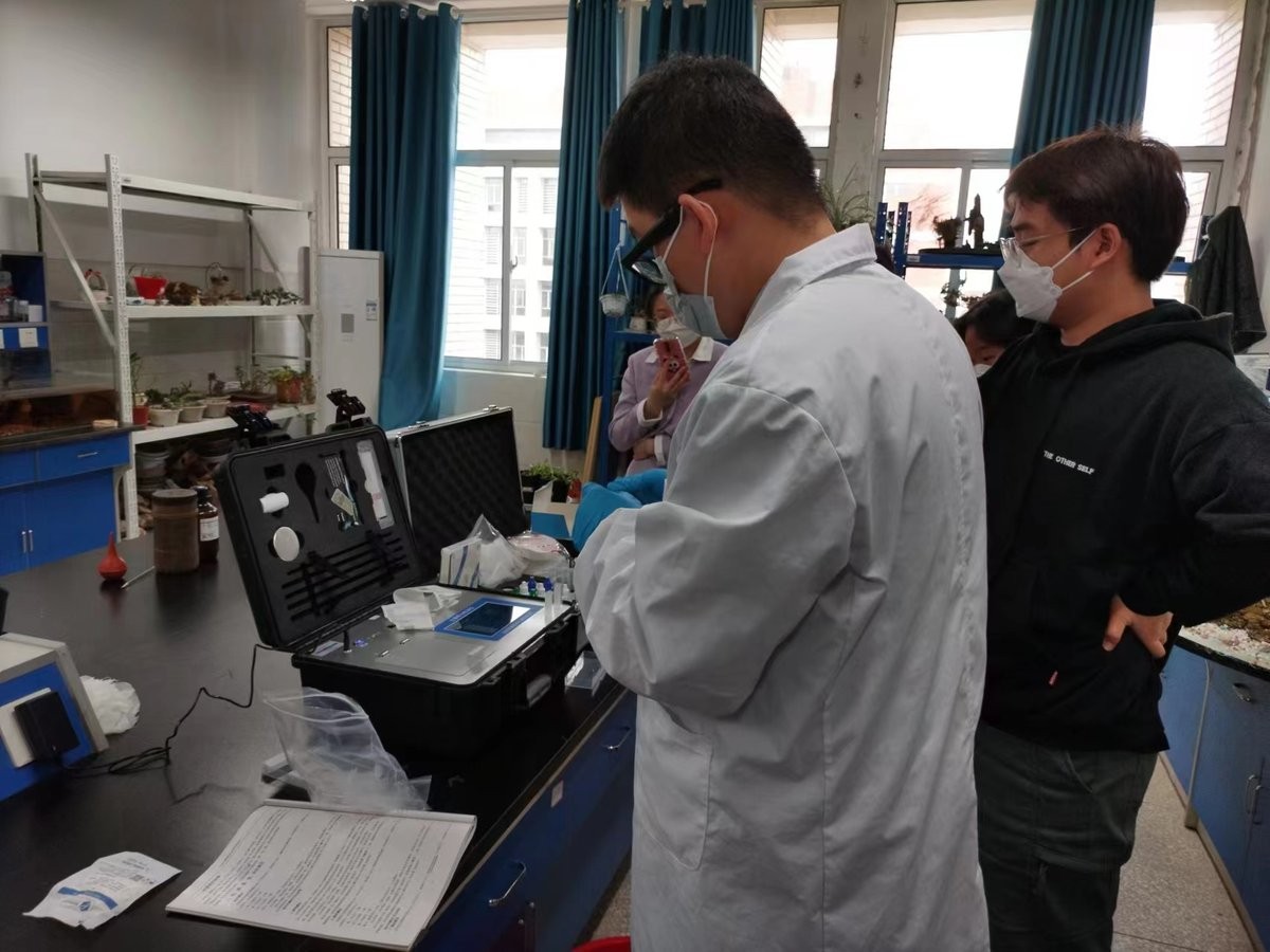 Instructor explaining HM-GT4 soil nutrient analyzer operation to trainees at Huainan Normal University