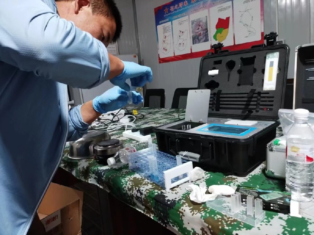 Instructor demonstrating HM-GT4 soil fertilizer tester reagent preparation on portable table at Xuechuan Agriculture Group field training site in Gansu